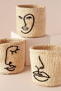 three woven baskets with faces drawn on them