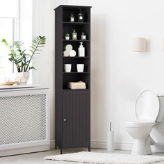 a white toilet sitting next to a tall wooden cabinet in a bathroom with a rug on the floor