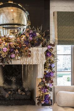 a living room with a fire place covered in purple flowers and greenery next to a fireplace