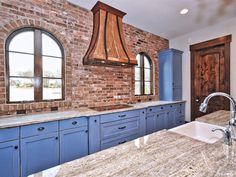 a kitchen with blue cabinets and an island countertop in front of a brick wall