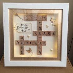 a wooden cross with words written on it in a white frame and some pearls around the edges