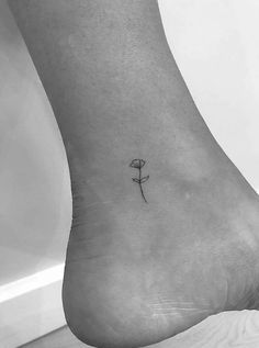 a single flower tattoo on the ankle is seen in this black and white photo,