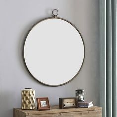 a round mirror hanging on the wall above a dresser