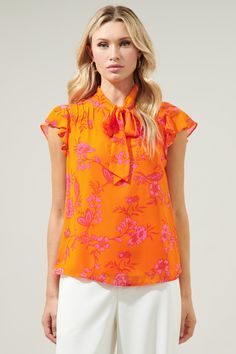 This top is like waking up to the brightest sunrise. Bold fuchsia floral motifs lay against this bright orange-ground. The vibrant print takes on the Cassius Blouse, featuring a tie neck detail to create a cut out at the chest. Pintuck pleats add a sweet touch to the shoulder, framing flutter cap sleeves. Wear it tucked in high waisted trousers for a completed look.- Tie neck detail- Lined- Pintuck pleats- Relaxed fit- Color: Fuchsia OrangeSize + Fit - Model is 5'10" and wearing size XS- Measure Pintuck Pleats, Color Fuchsia, Tie Neck Blouse, Fuchsia Color, Floral Motifs, Pin Tucks, High Waisted Trousers, Tie Neck, Bright Orange