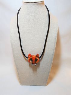 "Unique hand-made glass lioness head pendant in various shades of orange, white, and black. Red heart on reverse. Measures 1.5\" tall, 1.25\" wide. On a black cord that is 16\" long plus a 1.5\" extender." Hand Painted Adjustable Orange Jewelry, Adjustable Hand Painted Orange Jewelry, Shades Of Orange, Heart On, Orange White, Red Heart, Jewelry Necklace Pendant, Black Red, Pendant Necklaces