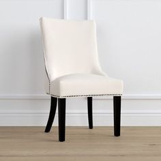 a white chair with black legs in front of a wall and hardwood flooring area