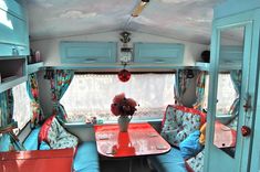 the interior of an rv with blue walls and red table, chairs, and couches