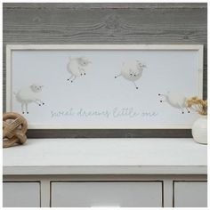 a white frame sitting on top of a dresser next to a vase and stuffed animal