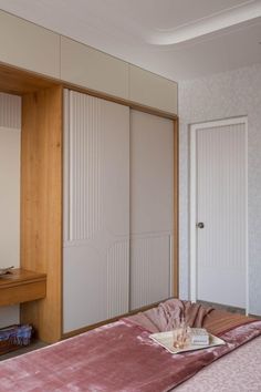 a bedroom with white closet doors and pink bedspread on the bed in front of it