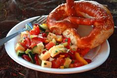 a white plate topped with a pretzel and salad