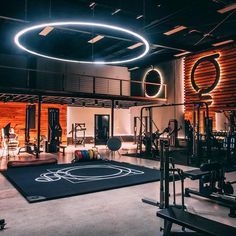 an indoor gym with exercise equipment and lights on the ceiling, surrounded by wood paneling