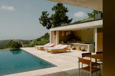 an outdoor swimming pool with chaise lounges next to it