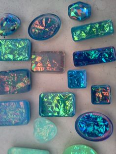 many different colored stones are arranged on a white surface with blue and green holographics