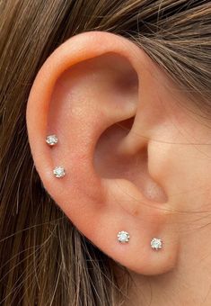 a woman's ear with three small diamond studs