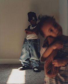 a little boy standing in front of a white wall