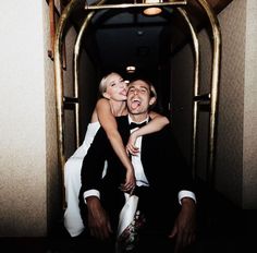 a man in a tuxedo is being hugged by a woman on a bus