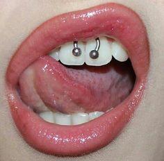 a woman's tongue with two piercings on top of her mouth and one in the middle