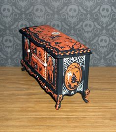 an orange and black halloween themed box on a wooden table with skulls in the background