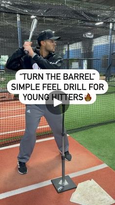 a man holding a baseball bat on top of a batting cage at a baseball field