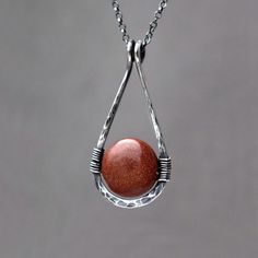 Goldstone Teardrop Necklace. Hammered Sterling Silver pendant. Autumnal terracotta brown / red gemstone jewellery. Created using beautiful Goldstone coin bead wire wrapped to a hammered hand forged sterling silver teardrop frame. Goldstone is a beautiful sparkly man-made `stone`; it is said that it was accidentally discovered by Italian monks practicing alchemy who split molten copper into molten glass. Metal particles are suspended within glass to give goldstone its striking twinkle, copper is used in the brown-red version of goldstone. Finished with a delicate sterling silver rolo style chain, adjustable in lenght and a lobster clasp. The frame has been hammered and hand polished for more strength and character. Available in bright or oxidized (darkened) sterling silver.  DETAILS  Stone Red Gemstone Necklace, Red Gemstone Jewelry, Bead Wire, Bohemian Chic Fashion, Hammered Sterling Silver, Red Gemstones, Teardrop Necklace, Teardrop Pendant, Gemstone Jewellery