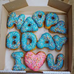 a box filled with lots of donuts covered in frosting and sprinkles