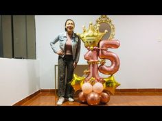 a woman standing in front of a large balloon number with balloons on top of it