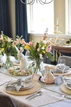 a dining room table set for easter with bunny figurines and flowers in vases