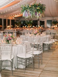 tables and chairs are set up in a tent with white linens, candles and flowers