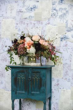 an old dresser with flowers on top and a vase full of flowers