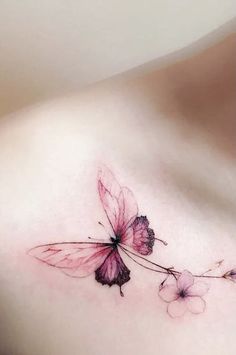 a woman's chest with a pink butterfly tattoo on the left side of her breast