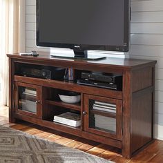 a flat screen tv sitting on top of a wooden entertainment center cabinet in a living room