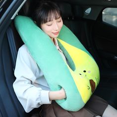 a woman sitting in the back seat of a car holding a pillow