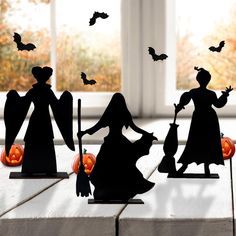 three silhouettes of people with bats and pumpkins on a table in front of a window