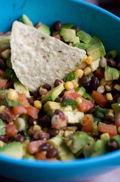 a blue bowl filled with black beans, avocado and tortilla chips