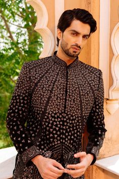 "Make an edgy statement with our ROYAL BLACK SHRUG INDO WESTERN designed thoughtfully for the modern Indian man. A fusion staple fit for every occasion, adds the right amount of cultural twist to the western silhouette. Color: Black Neck: Mandarin Collar Fabric: Saphire Fabric Embroidery: Kashmiri Embroidery Garment Type: Shrug Indo Western The Product Price is inclusive of: 1 Upper Indo-Western, 1 Sleeve-less Inner Indo-Western and 1 Trouser Style Bottom Model is 6'2\" wearing Size 38 Product color may slightly vary due to photographic lighting sources or your screen settings." Jodhpuri Sherwani For Men, Men Jodhpuri, Jodhpuri Sherwani, Jodhpuri Suit For Men, Jodhpuri Suits For Men, Indian Jackets, Jodhpuri Suit, Embroidered Sherwani, Black Shrug