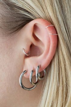 a woman with blonde hair wearing two silver hoop earrings on her left ear and one in the middle