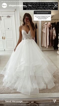 a woman taking a selfie in front of a mirror wearing a white wedding dress