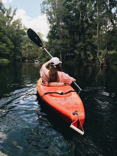 a woman in a red kayak paddles through the water