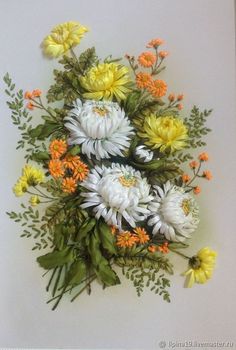 an arrangement of flowers arranged on a white surface with green leaves and orange blooms in the center