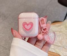 a hand holding an apple airpods case with hearts on it and a pink bow