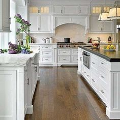 a large kitchen with white cabinets and black counter tops, along with an island in the middle