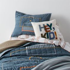 a bed with two pillows and a pillow on top of it, both have the words hey kid printed on them