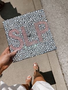 a person holding up a sign made out of balls on the sidewalk with their feet