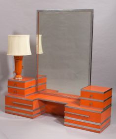 an orange dresser with mirror and lamp on it