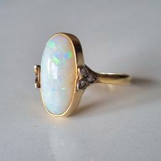 an opal and diamond ring on a white surface