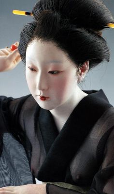 a geisha woman with two yellow sticks in her hair