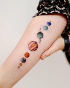 a woman's arm with different planets on it