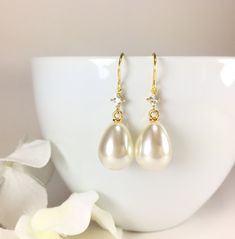 "Pearl Earrings, Gold Pearl Earrings, Simple Pearl Earrings, Pearl Dangle Earrings, Long Dangle Earrings, Minimal Earrings, Pearl Teardrop Earrings, CZ Pearl Earrings, Wedding Bridal Earrings, Bridesmaid Gift, Pearl Jewelry, Gift for Her Minimal classic design, these lovely earrings are composed of a large 21x13mm faux teardrop pearl dangling from a small diamond shaped CZ accent stone and simply hung from gold plated ear wires. Dangle length is 1-1/2\" (40mm) from the top of ear wire. Discount White Teardrop Earrings For Bridal Shower, White Teardrop Bridal Earrings For Bridal Shower, Classic Pear-shaped Pearl Earrings For Wedding, Delicate Gold Teardrop Earrings For Wedding, Classic Teardrop Crystal Earrings In White, Elegant Teardrop Earrings For Bridesmaid Gift, Classic White Teardrop Crystal Earrings, Classic Teardrop Pearl Earrings For Wedding, Pear Shaped Teardrop Earrings With Pearl Drop For Wedding