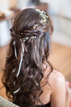 the back of a woman's head with long hair and flowers in her hair