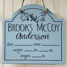 a blue wooden sign hanging from the side of a white wall that says brooks mccy and has winnie the pooh on it